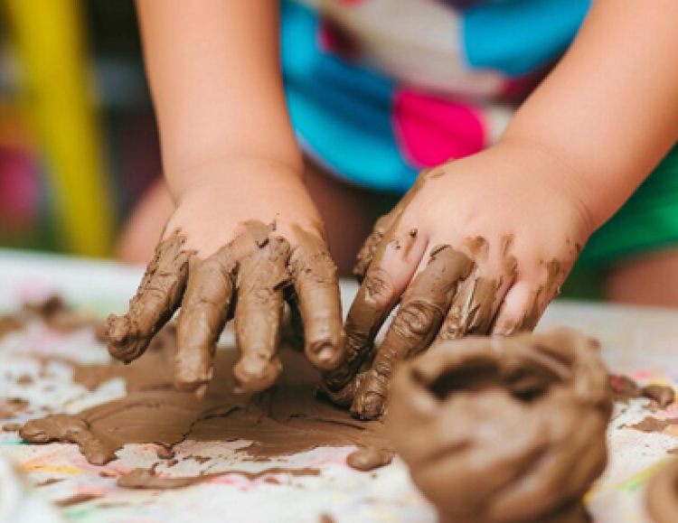 A young child shaping clay with both hands